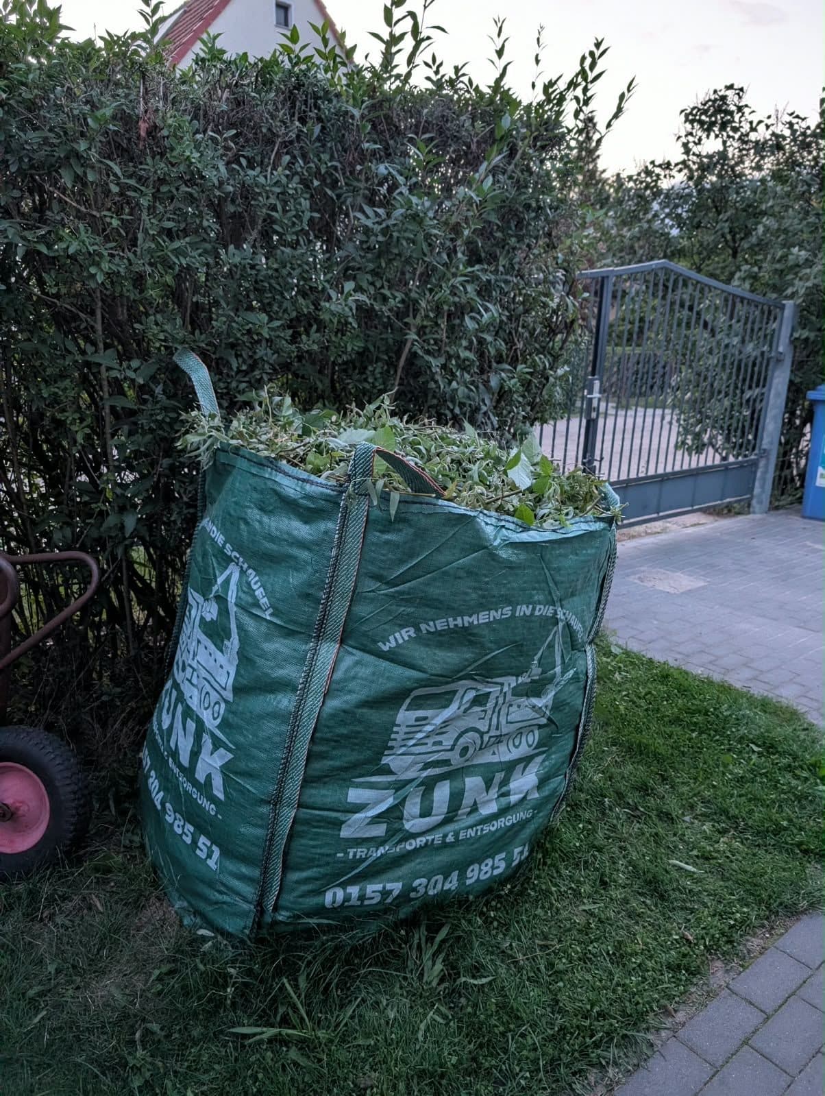 Big Bag mit Gartenabfällen Kleiner grüner Zunk Big Bag, gefüllt mit Gartenabfällen, in einem Vorgarten